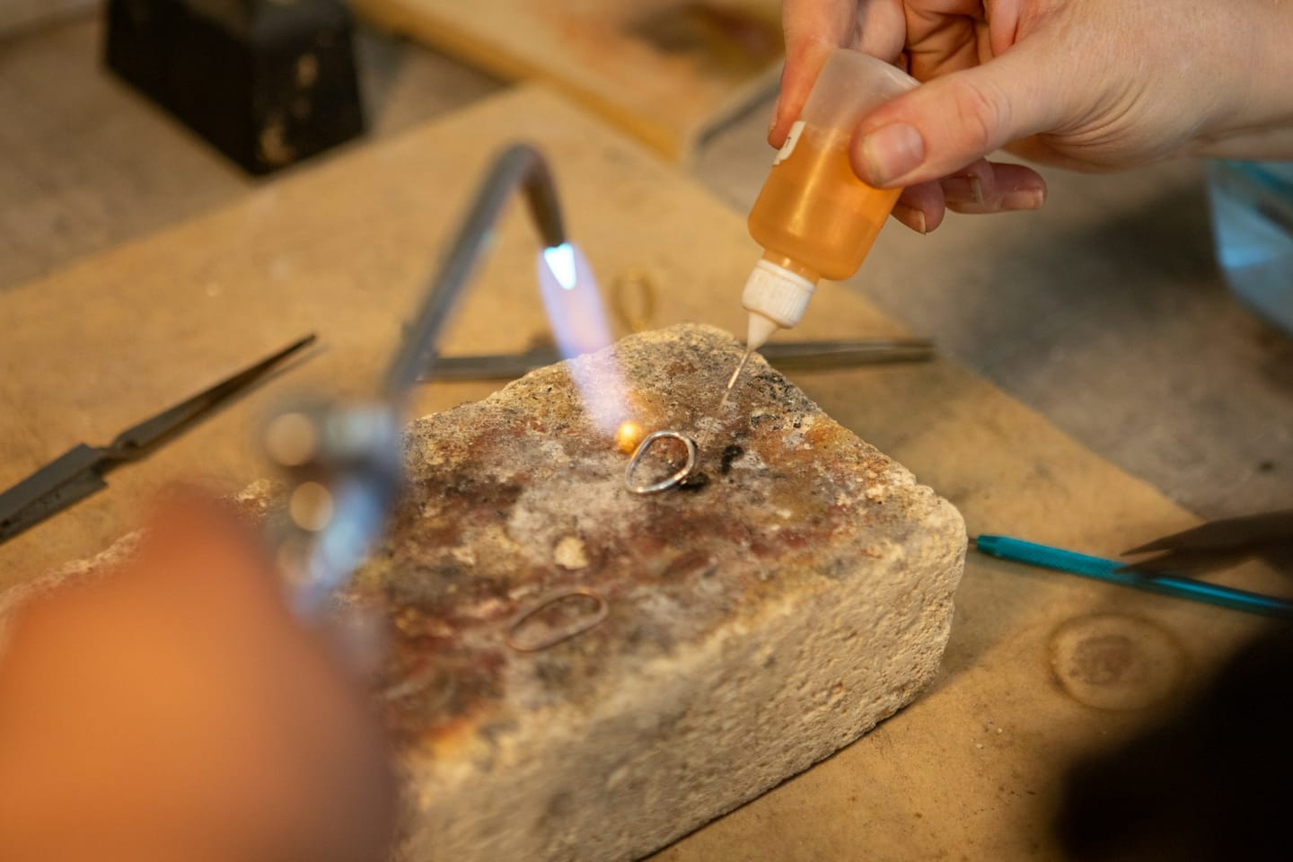 Jeweler soldering a ring with a torch and flux.
