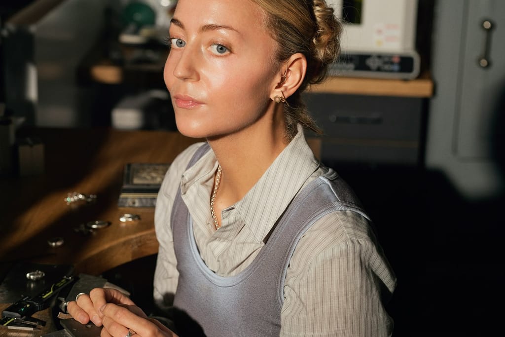 A young woman working at a jewelry bench.