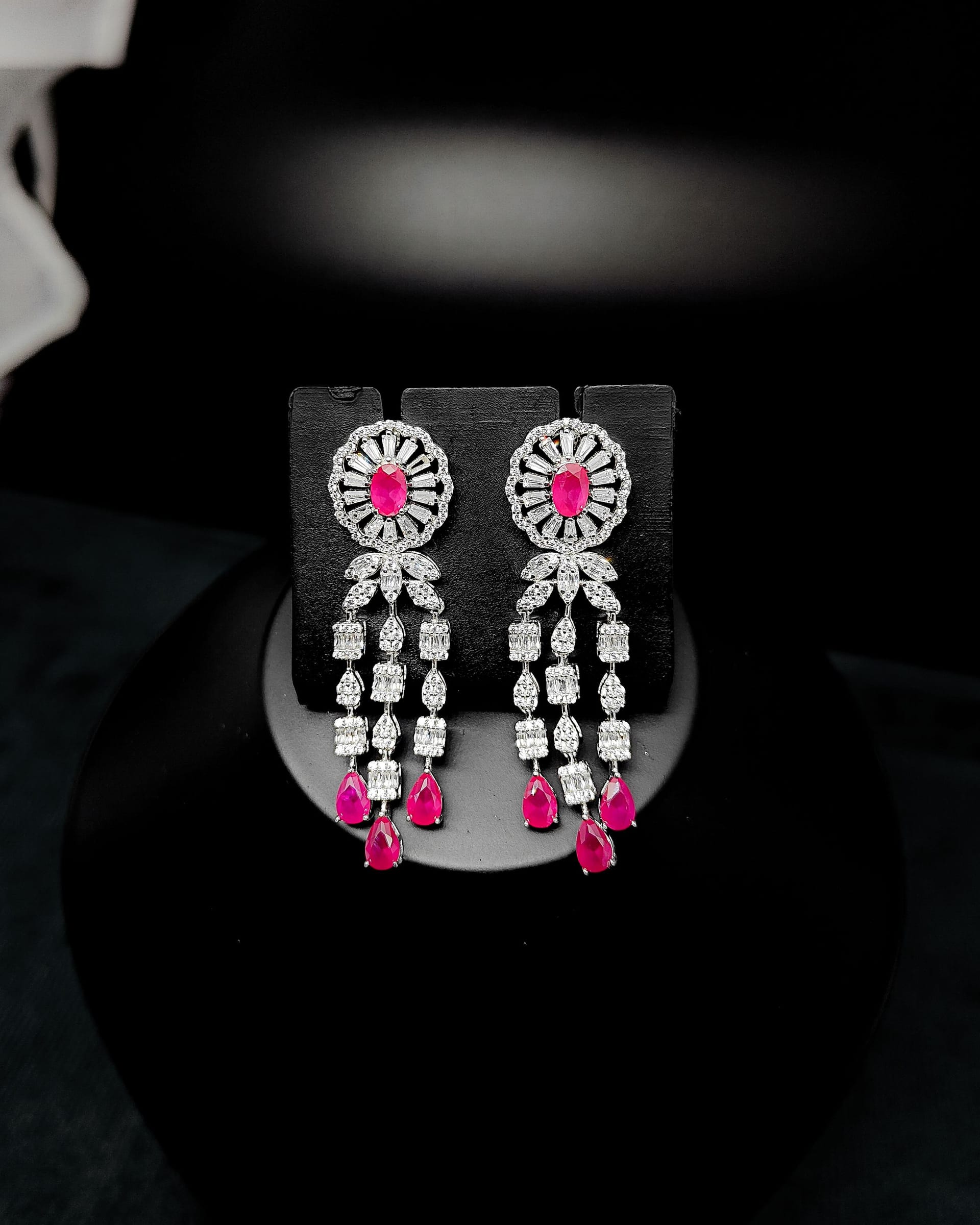 Long silver-toned drop earrings with oval and pear-shaped rubies and bright accent stones.