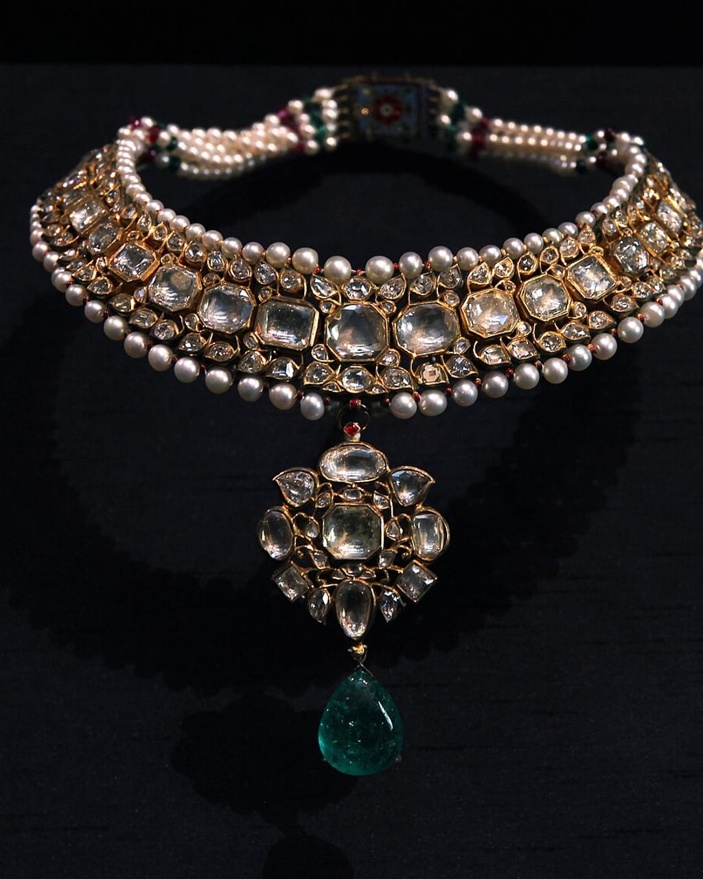 Indian kundan collar necklace bordered with pearls and centred by an emerald drop.