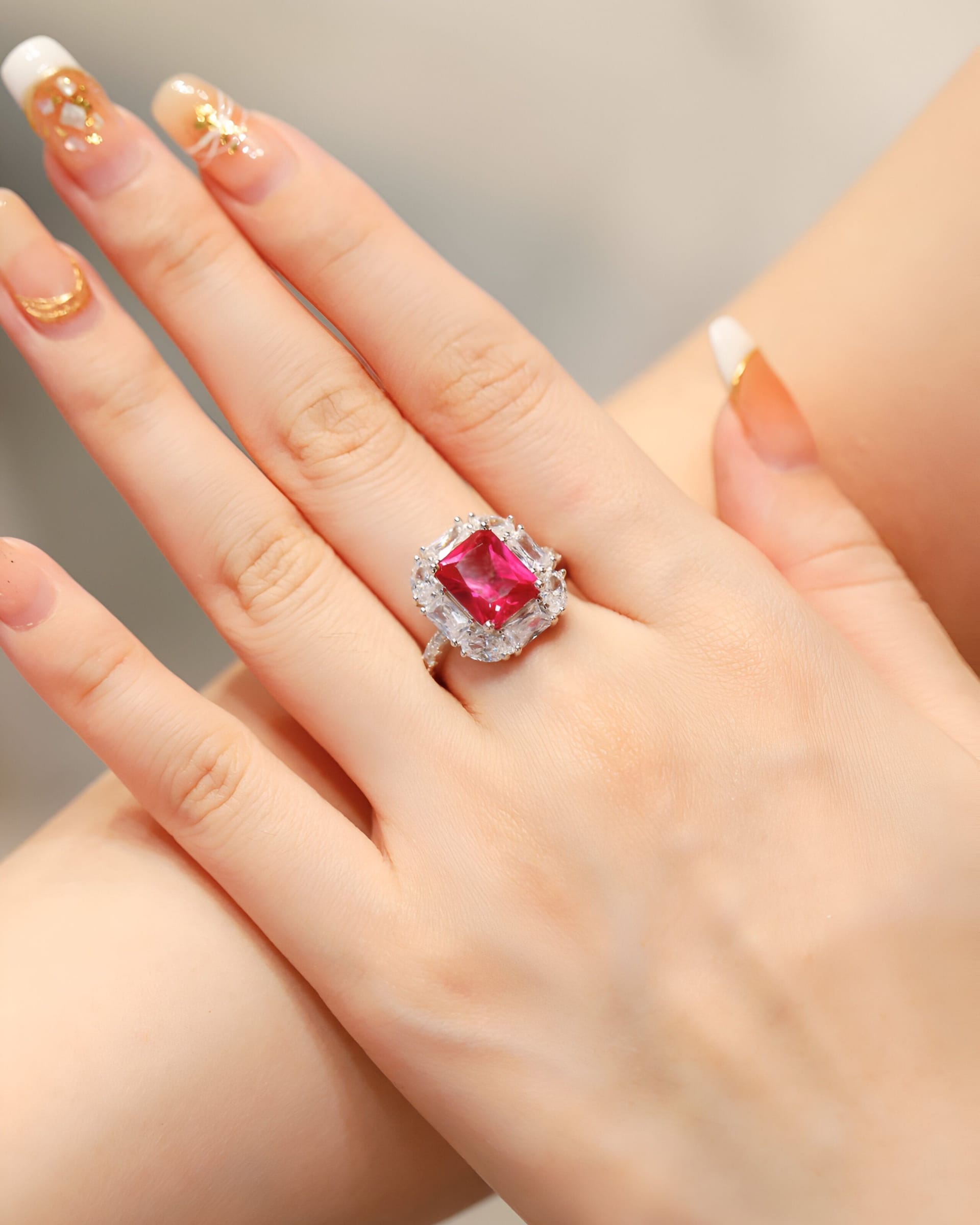 Rectangular ruby cocktail ring with a bright halo in a white-metal setting.